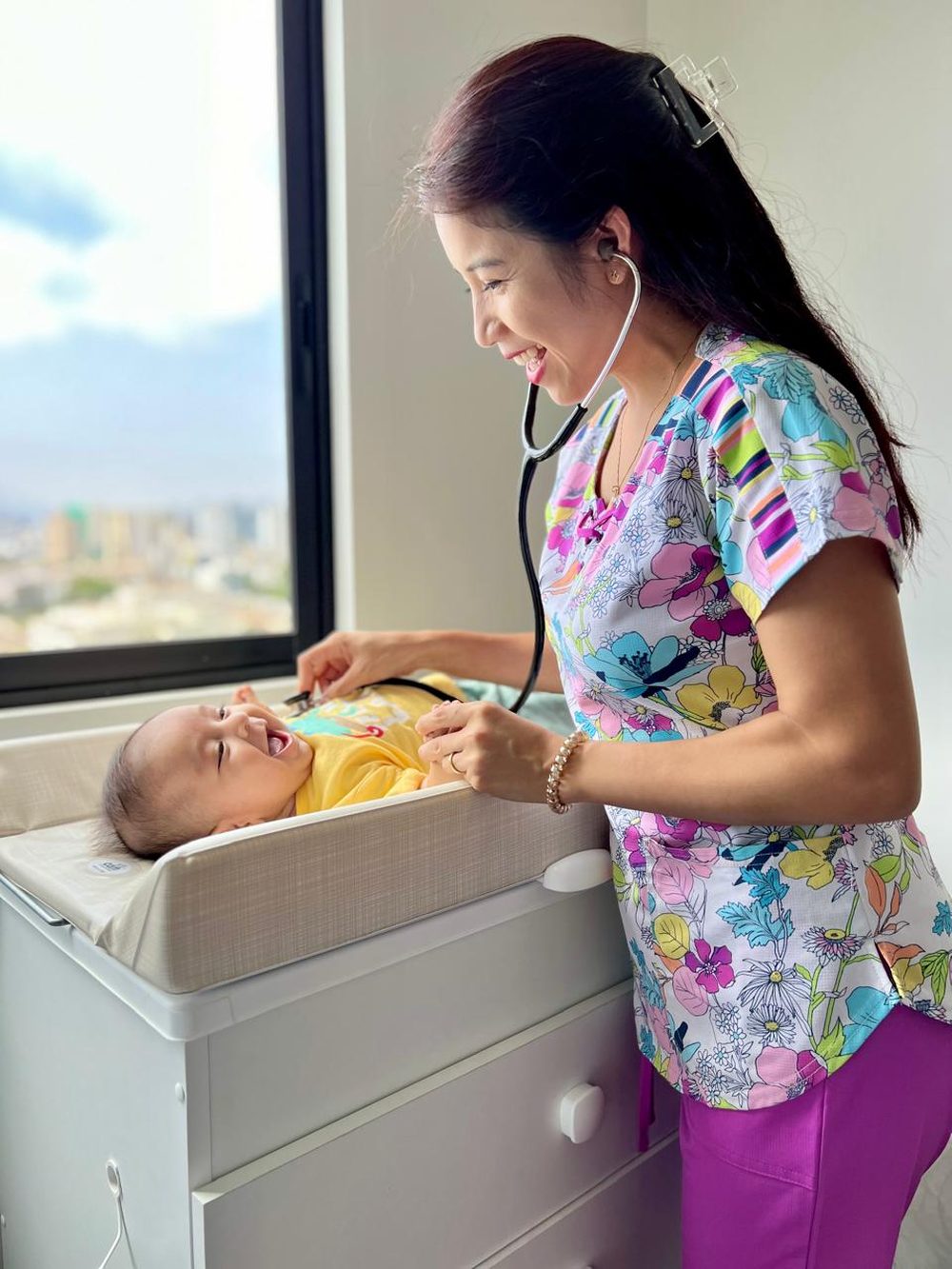 Dra. Carolina Yi auscultando a un bebé sonriente